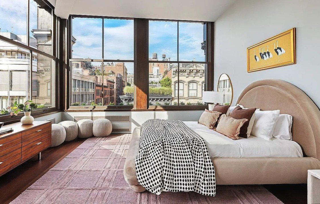 Corner bedroom with tall windows overlooking SoHo's cast-iron buildings and water towers